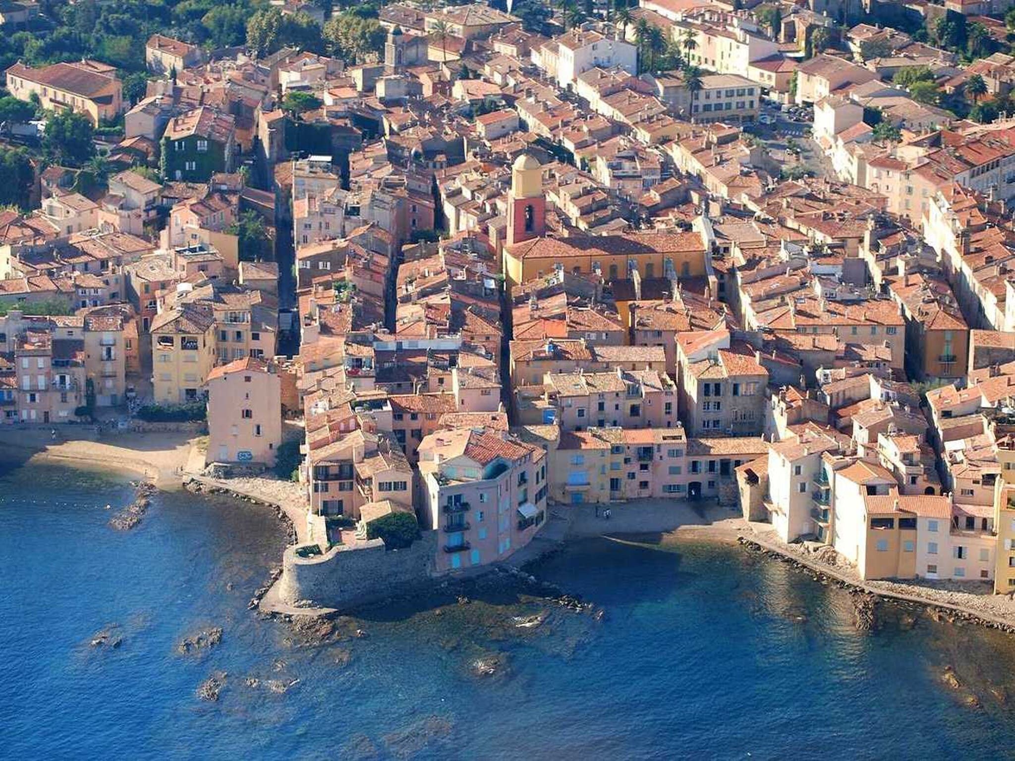 A coastal town with closely packed buildings, a prominent church, and a beach area.