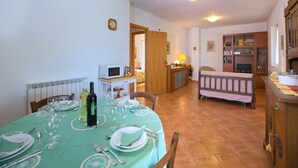 Een eetruimte met een tafel voor vier personen, een keuken op de achtergrond en een gezellige zithoek met een bank en een open haard.
