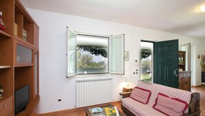 Een gezellige woonkamer met een bank, een bijzettafeltje en een televisie op een houten kast.