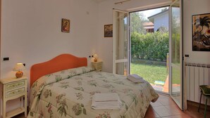 Een slaapkamer met een bed, nachtkastje, lamp en uitzicht.