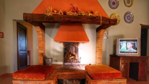 A cozy room with a brick fireplace, two cushioned benches, a television, and decorative plates on the wall. - Farmhouse in Tuscany near Bibbiano Castle (Montalcino)
