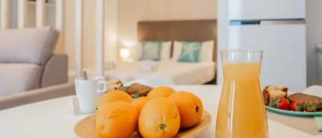 A breakfast setting with oranges on a plate, a glass of orange juice, and a plate of toast and strawberries on a table.