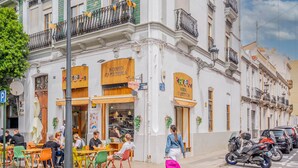 Una calle con terraza para restaurantes, una mujer empujando un cochecito y motocicletas estacionadas.
