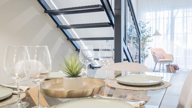 A dining area with a glass table set for a meal, surrounded by chairs. - Loft HomeValencia by Host Valencia (Valencia)