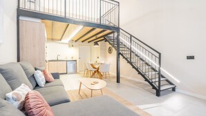 A modern living room with a grey sofa, a wooden dining table, and a staircase leading to an upper level. - Loft HomeValencia by Host Valencia (Valencia)