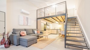 A modern living room with a grey sofa, a coffee table, and a staircase leading to an upper level. - Loft HomeValencia by Host Valencia (Valencia)
