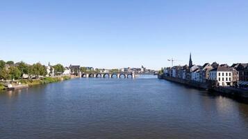 A river with a stone bridge, buildings along the riverbank, and a clear sky.