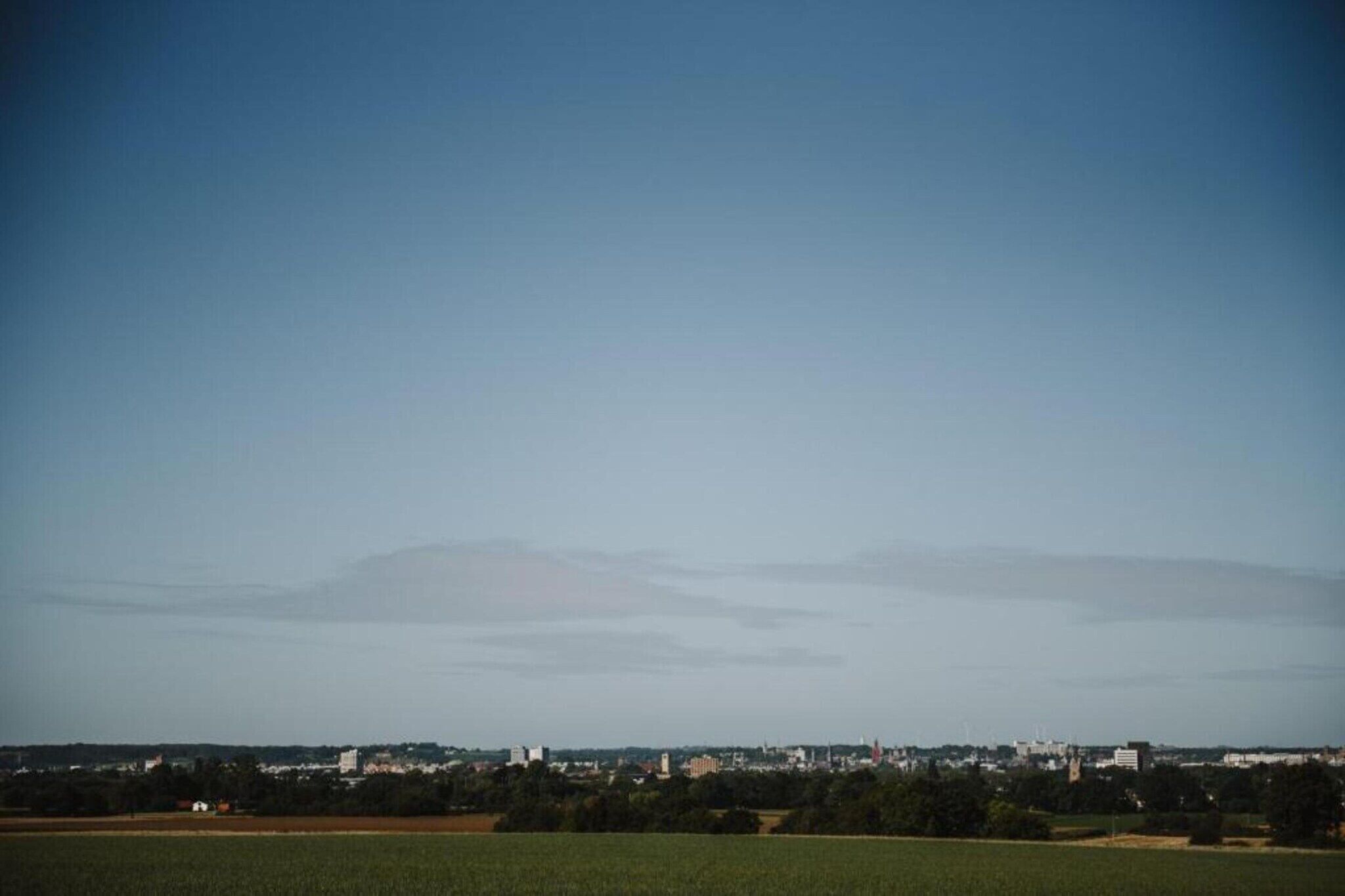 Une vue d’ensemble d’une ville, avec une montagne imposante en arrière-plan, un ciel dégagé et un paysage plat au premier plan.