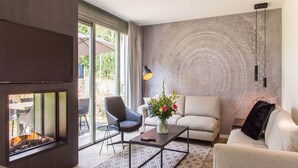 Ein modernes Wohnzimmer mit Kamin, einer Couch, einem Couchtisch und einem großen Fenster mit Vorhängen.