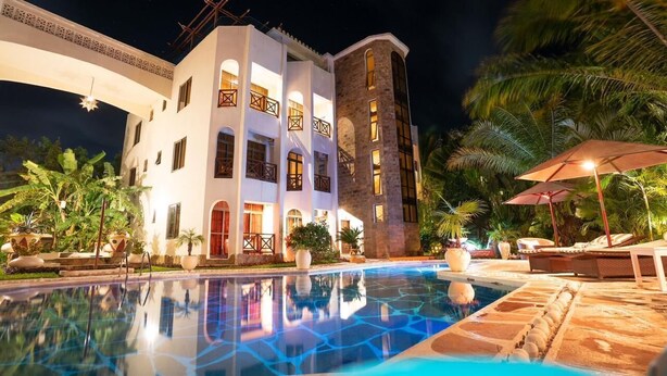 Ein Hotel mit Pool, Außenbereich und einer gut beleuchteten Fassade bei Nacht.