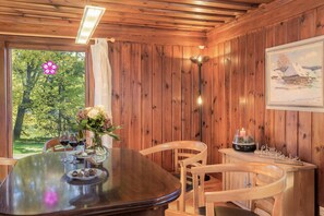 A wooden-paneled room with a dining table, chairs, a vase with flowers, a candle, and a painting on the wall. - Altes Forsthaus Kniebis | almost secluded location | historic | dog | barbecue | WLAN (Freudenstadt)