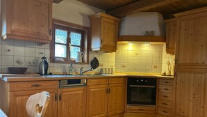 Una cocina con armarios de madera, lavavajillas, horno y una ventana con cortinas.