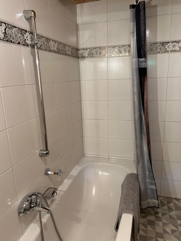Un baño con bañera, ducha y perchero.