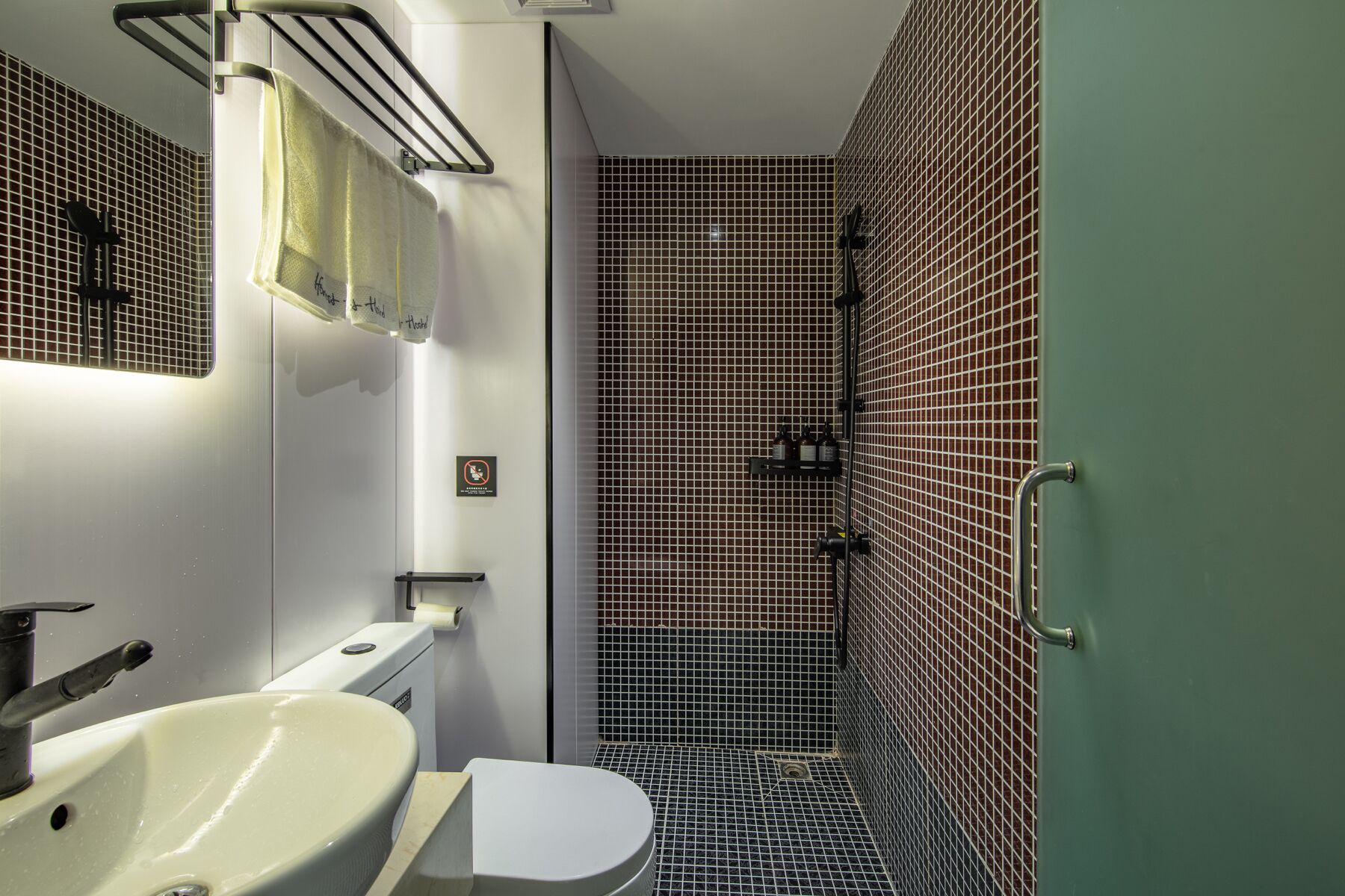 A bathroom with a white sink, a toilet, and a shower area with a tiled floor.