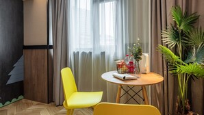 A room with a round wooden table, two yellow chairs, a potted plant, and a window with sheer curtains. - Iforest Hongkou Football Stadium (Shanghai)