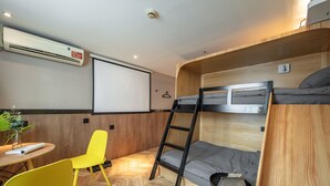 A compact room with bunk beds, a desk, a chair, and an air conditioning unit. - Iforest Hongkou Football Stadium (Shanghai)