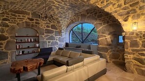 Una habitación con paredes de piedra, un ventanal grande, un sofá y una mesa de centro de madera.
