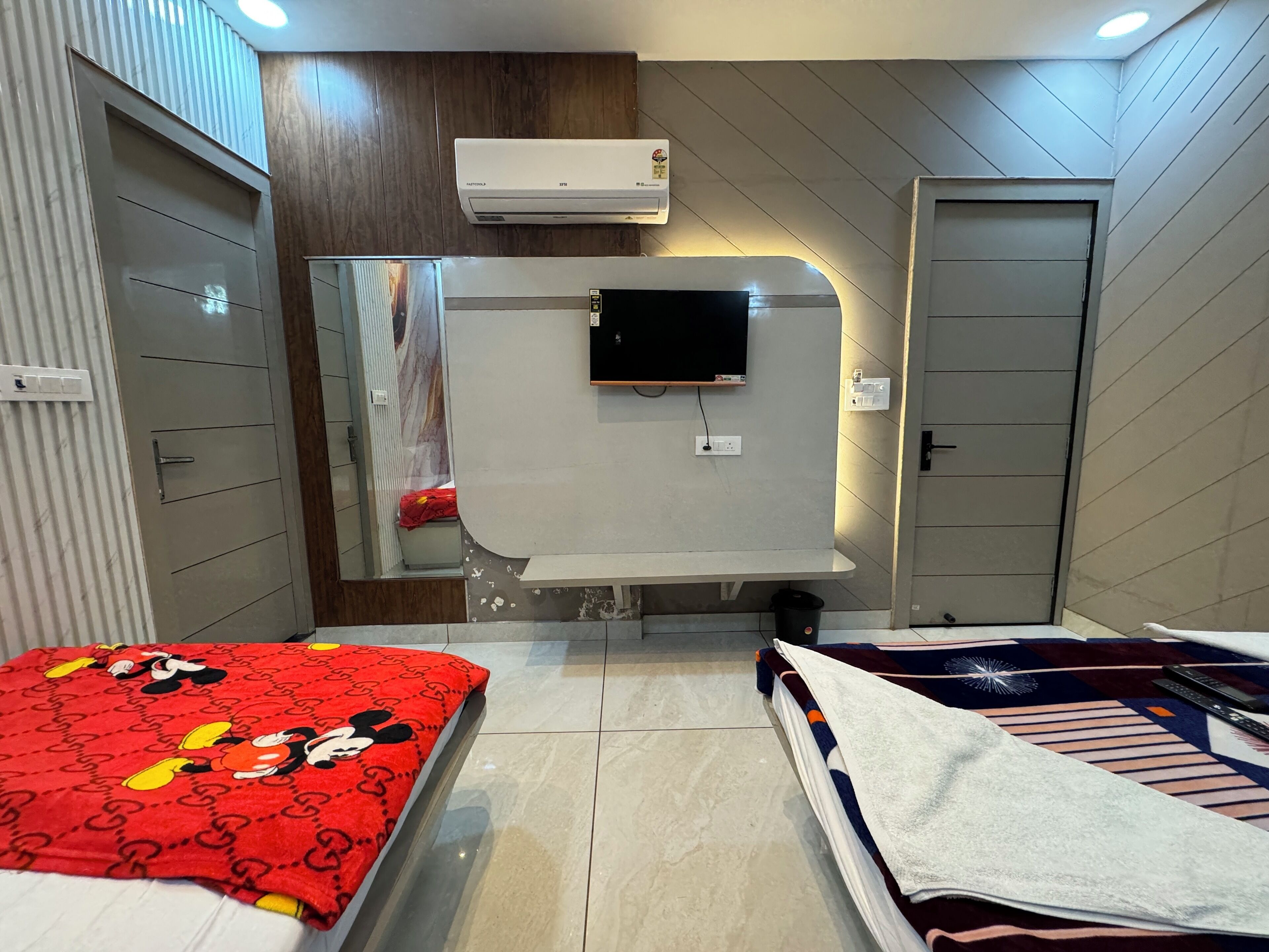 A bedroom with a bed, a TV, a wardrobe, and an air conditioning unit.