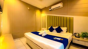 Quarto de hotel com cama, mesa de cabeceira, aparelho de ar condicionado e ventilador de teto.