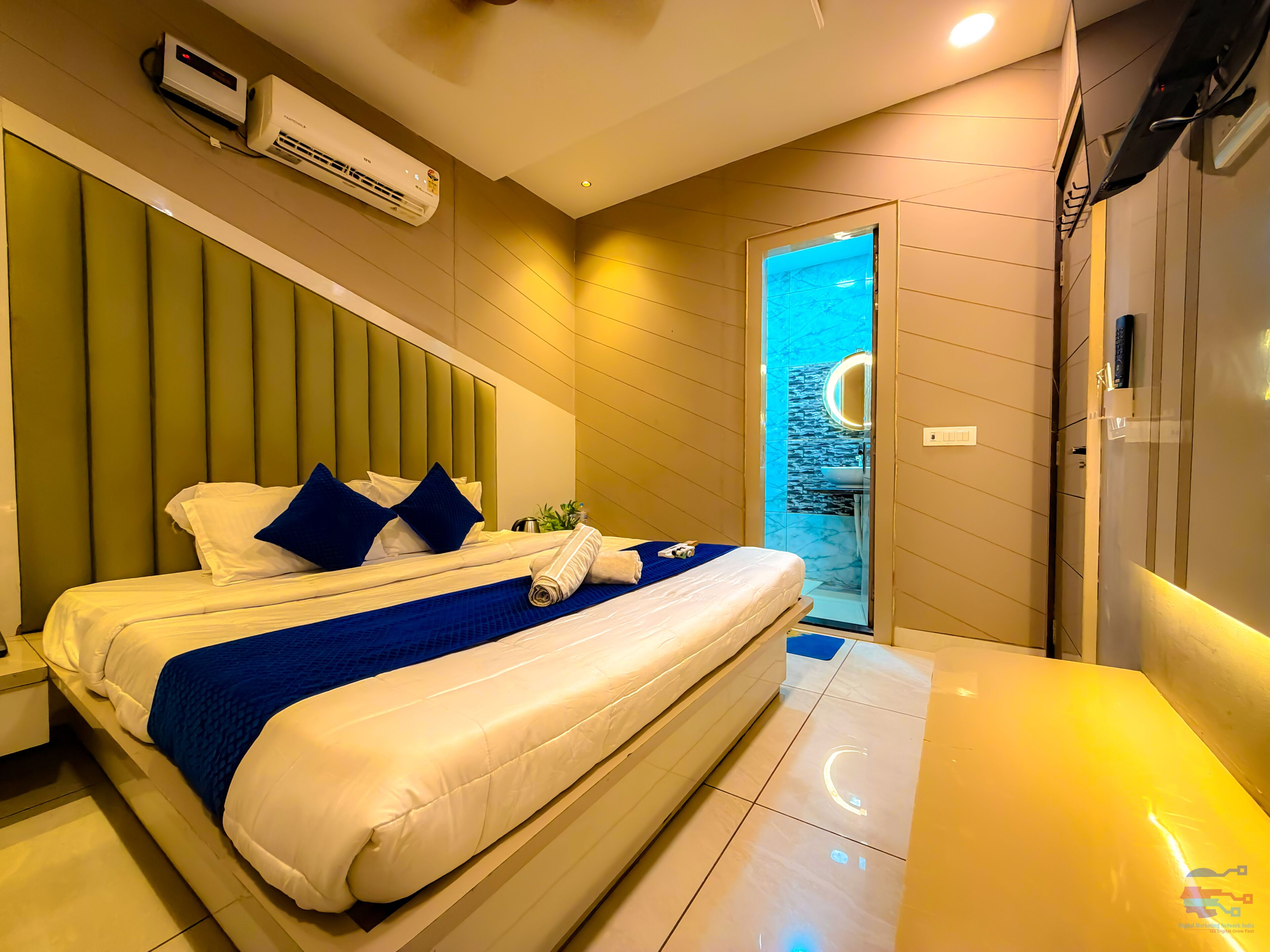 Une chambre d’hôtel moderne dotée d’un grand lit, d’un système de climatisation intégré et d’une salle de bain avec un mur recouvert de carreaux bleus.