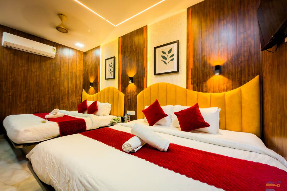 A hotel room with two beds, wooden paneling, wall-mounted lights, and an air conditioning unit.