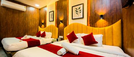 Quarto de hotel com duas camas, painéis de madeira, luminárias fixadas na parede e um aparelho de ar condicionado.