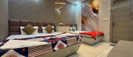 A modern bedroom with a large bed, a smaller bed, and a desk.