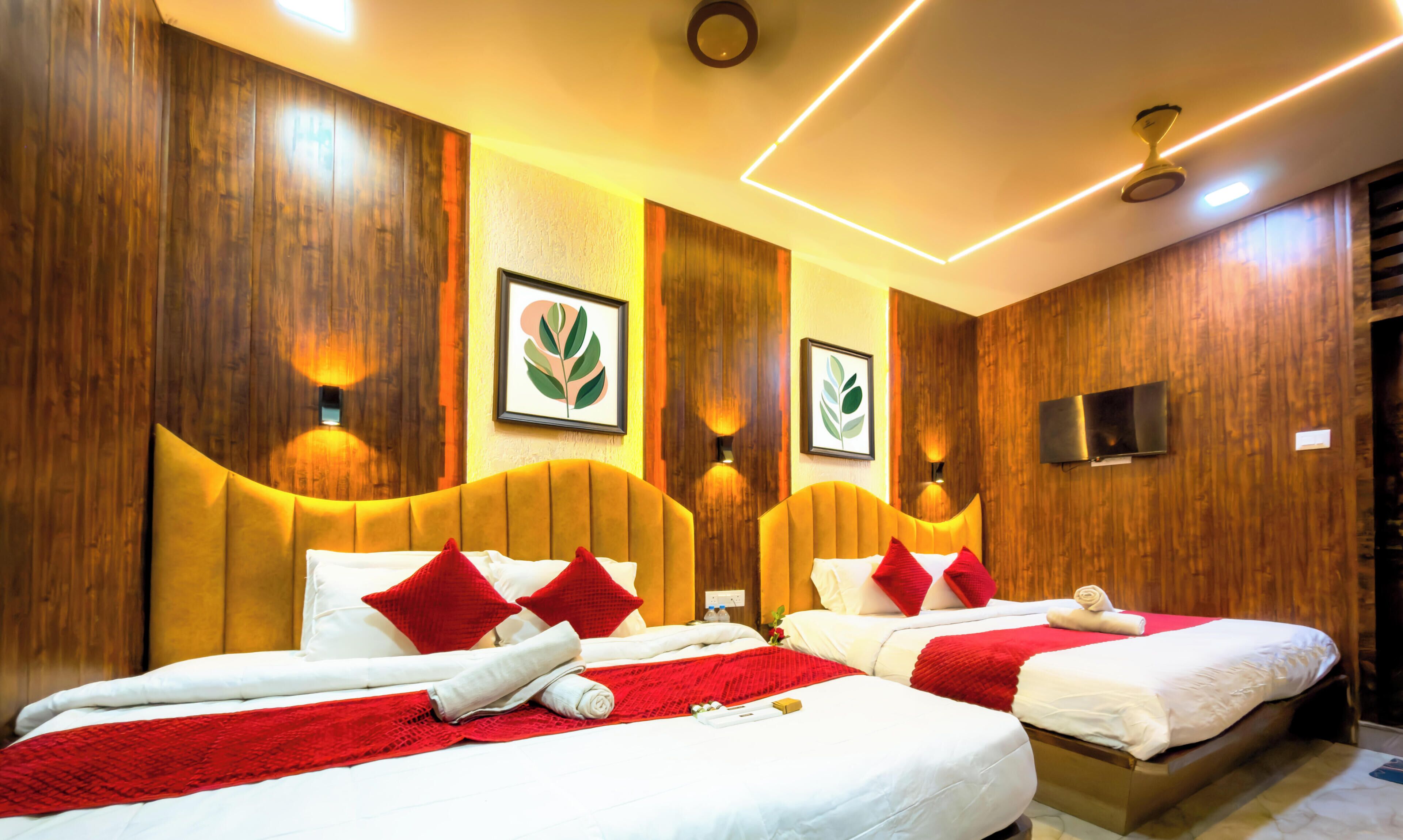 A hotel room with two beds, wooden paneling, wall-mounted artwork, and ceiling lights.