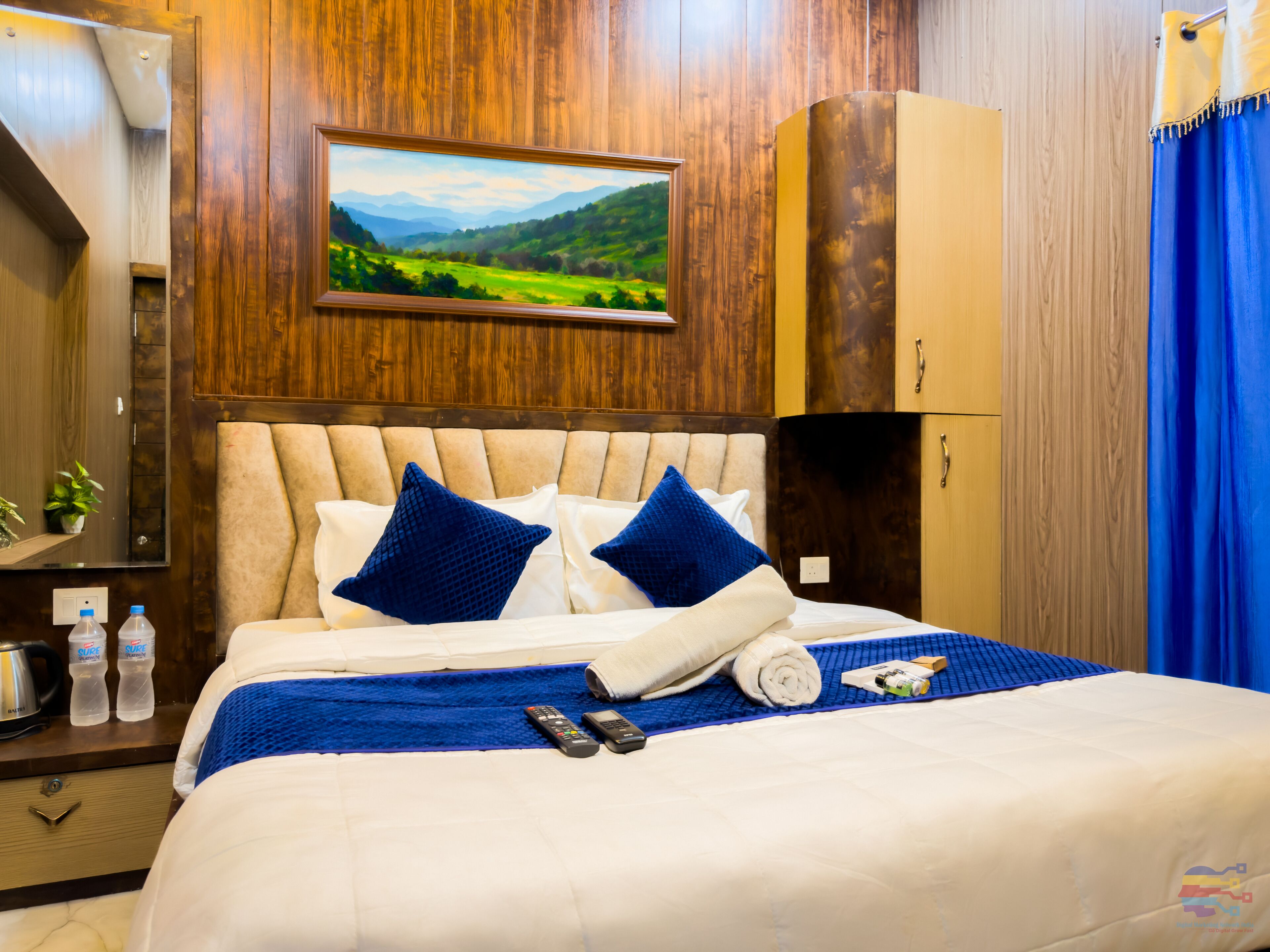 A hotel room with a bed, a painting, a wardrobe, and a bathroom.
