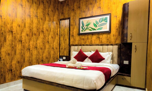 Quarto de hotel com parede de madeira, cama com roupa de cama branca, almofadas vermelhas e uma obra de arte com planta emoldurada.