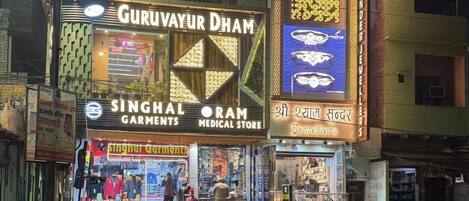 A street view at night with a medical store and a jewelry shop.