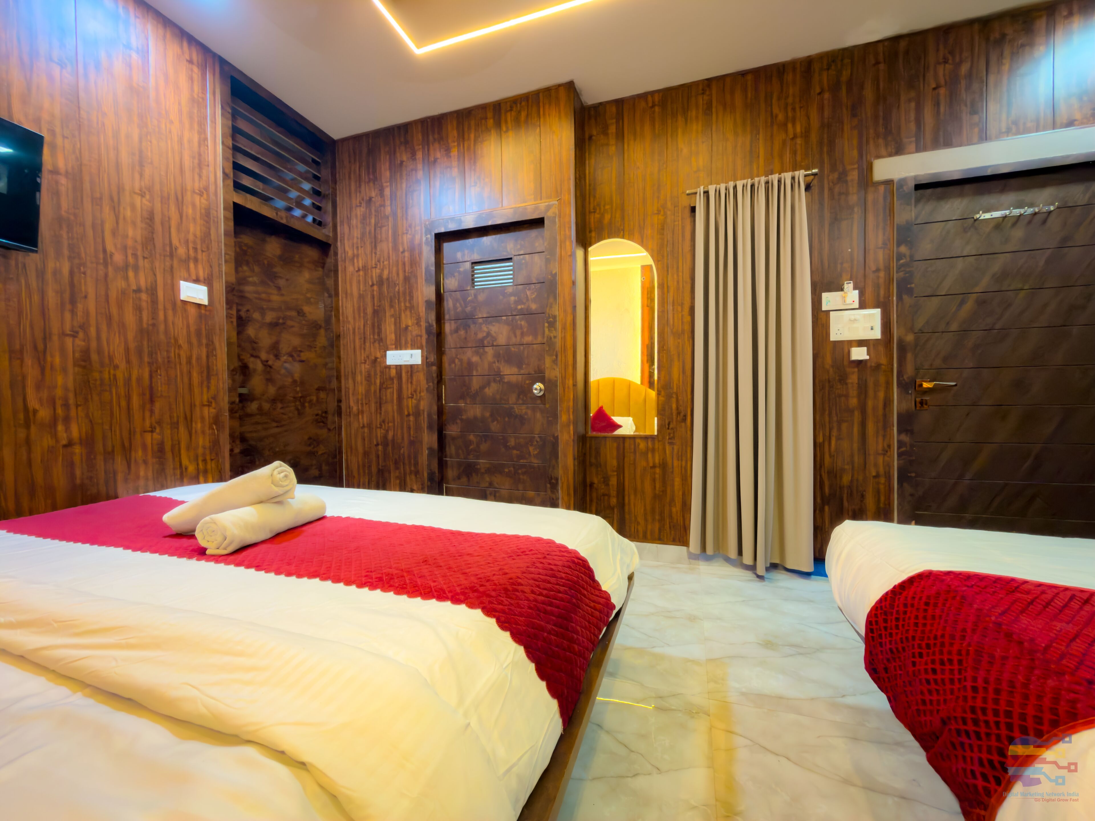 Une chambre d’hôtel avec deux lits, des lambris en bois, un miroir et une couvre-lit rouge et blanche.