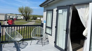 A mobile home with a balcony featuring two white chairs and a sign indicating 'Summer Days'. - Luxury holiday Home close to Padstow and beautiful beaches  (Saint Merryn)