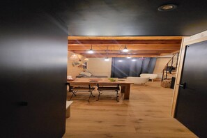 A modern interior with a wooden dining table, benches, and a sofa.