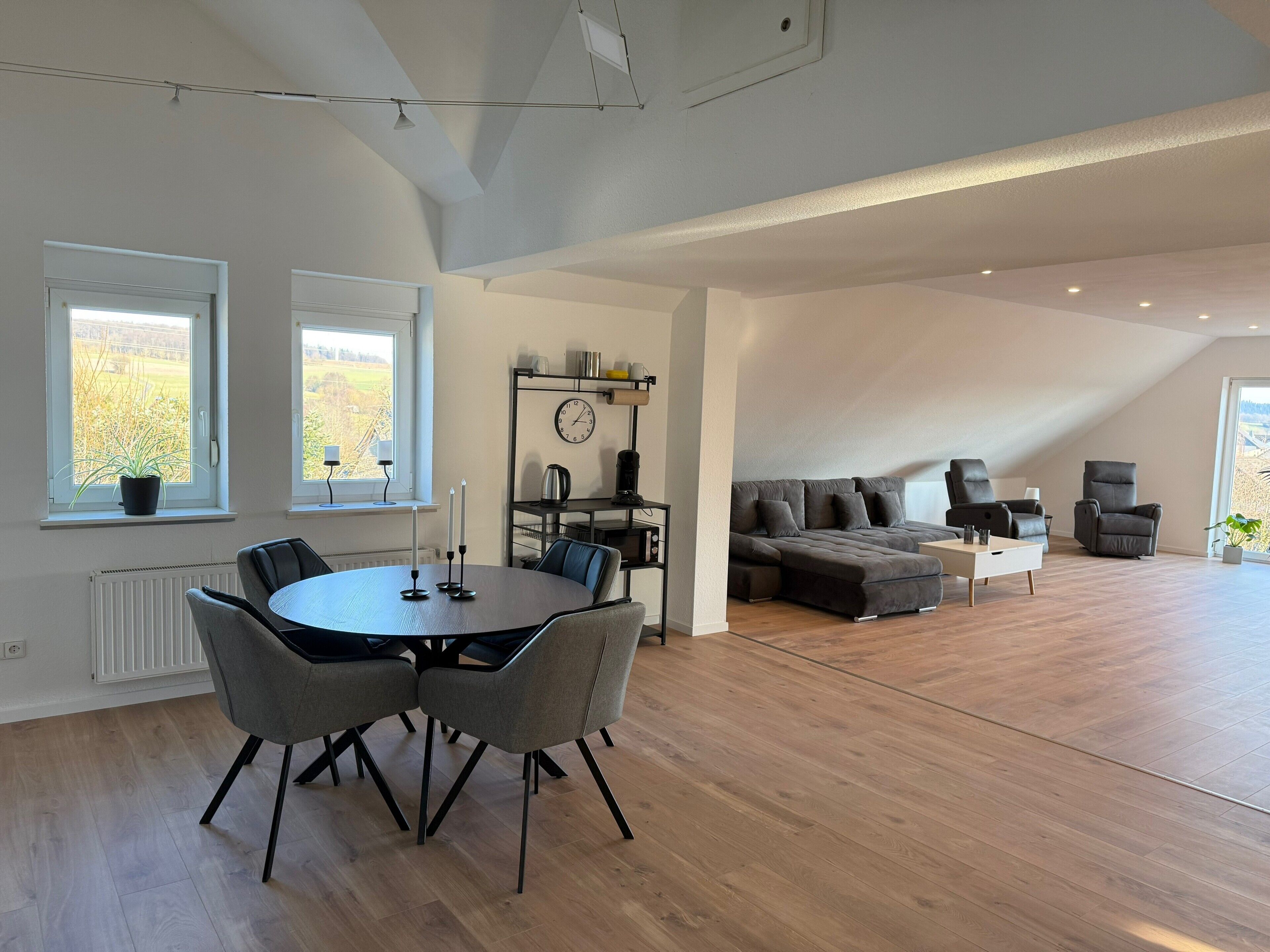 Een ruime loft met een eethoek, een bank en een stoel.
