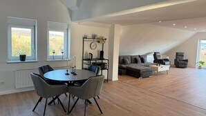 A spacious loft with a dining area, a sofa, and a chair. - Apartment 'Waldblick Alterkülz' with Wi-Fi (Alterkülz)