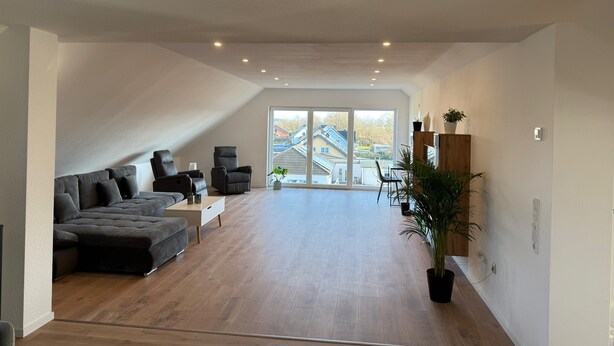 A spacious living area with a large sofa, two armchairs, a coffee table, and a dining table with chairs. There is a large window providing a view of the outside. - Apartment 'Waldblick Alterkülz' with Wi-Fi (Alterkülz)