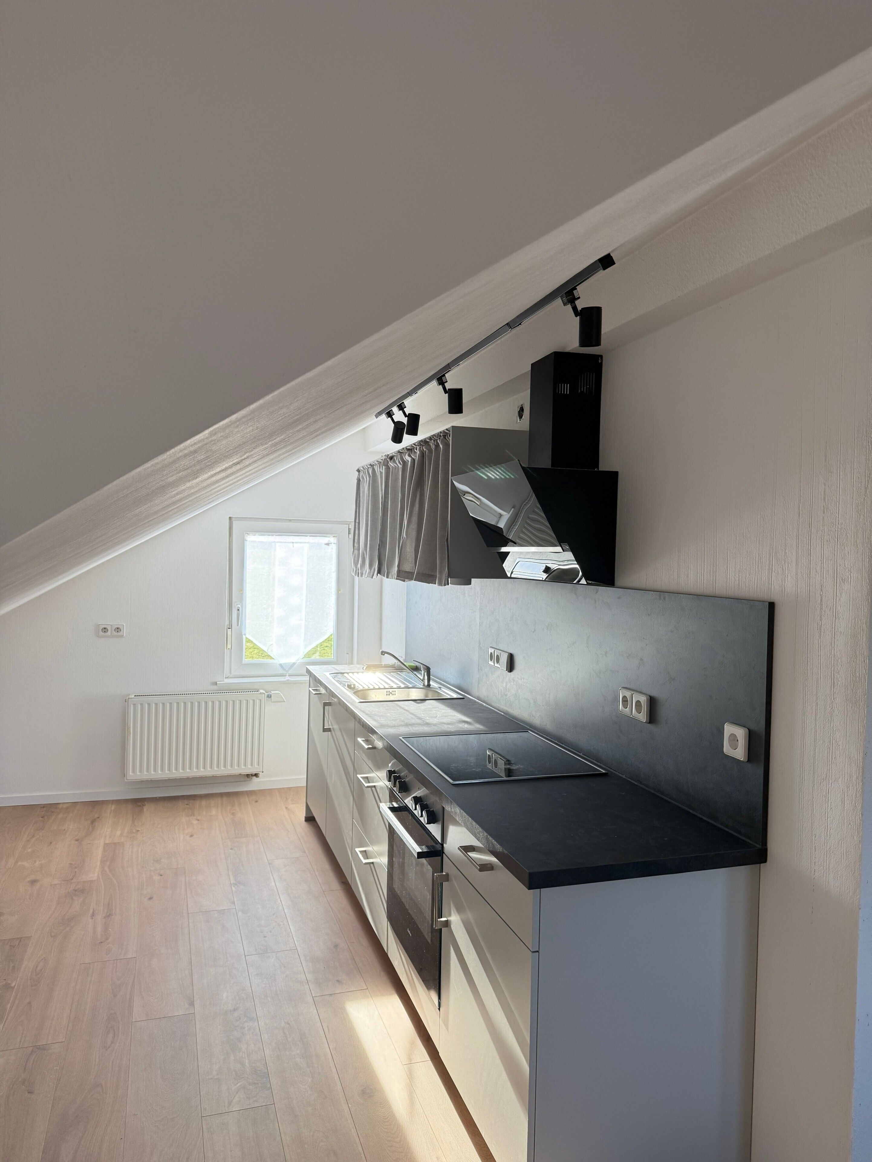 Moderni keittiö, jossa on sisäänrakennettu uuni, pesuallas ja ikkuna.