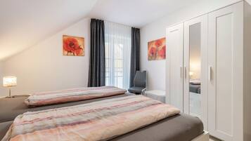 Ein Schlafzimmer mit zwei Betten, einem Schreibtisch, einem Stuhl, einem Kleiderschrank und Bildern an den Wänden.