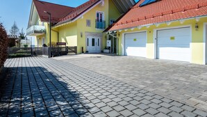 Um edifício amarelo com telhado de telhas vermelhas, portão e entrada com calçada.