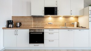 Cozinha moderna com armários brancos, micro-ondas, fogão e cafeteira.