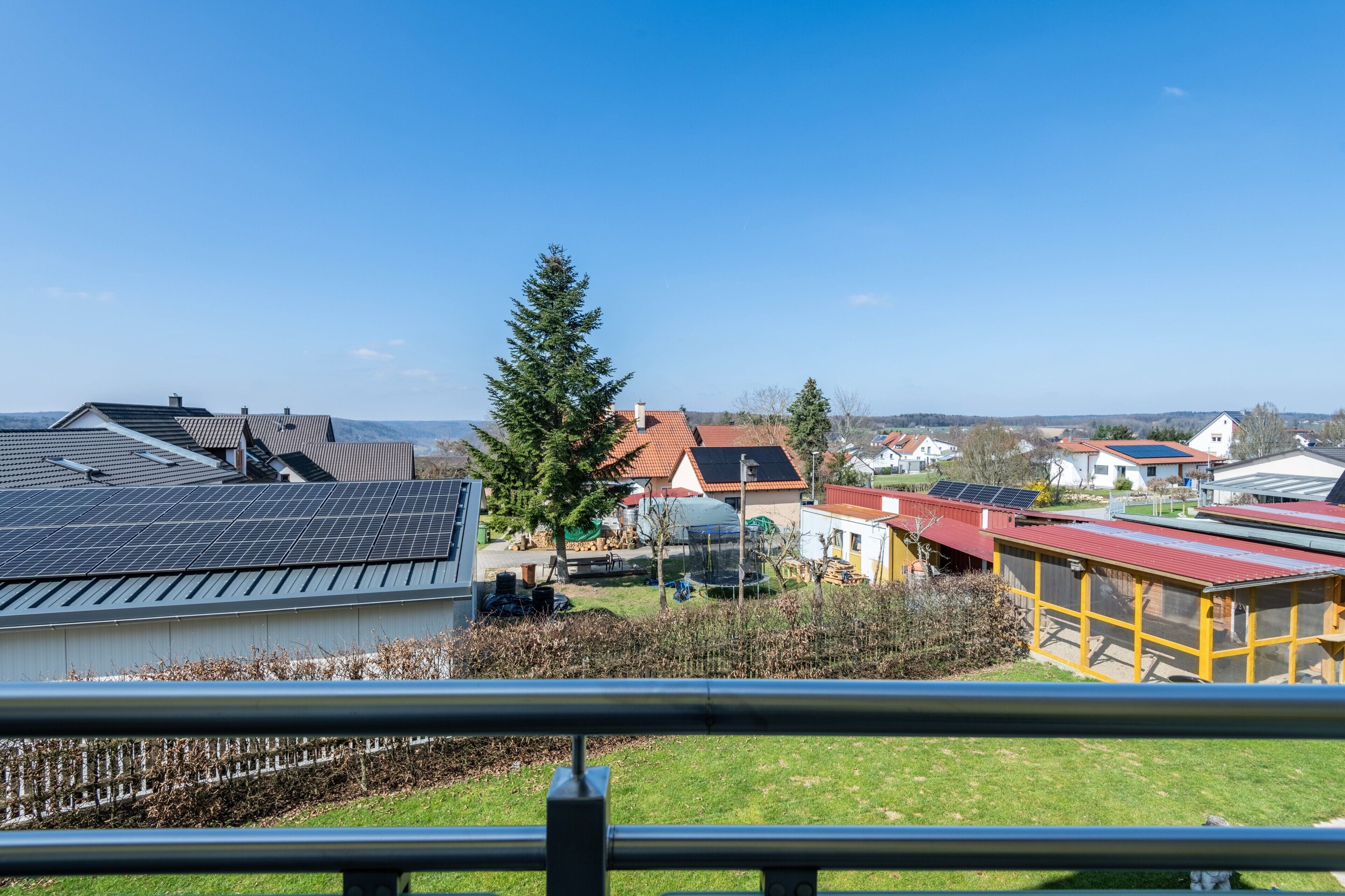 Un quartier résidentiel avec des maisons, des panneaux solaires et un grand arbre.