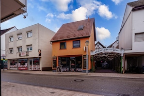 Une vue de rue avec un bâtiment portant l’inscription « Otkel’skleine Bar » et un autre bâtiment avec une enseigne « Friseur ».