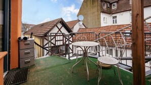 A rooftop terrace with a table and chairs, a metal staircase, and a building with a tiled roof. - Apartment 'C' with Wi-Fi (Bühl)