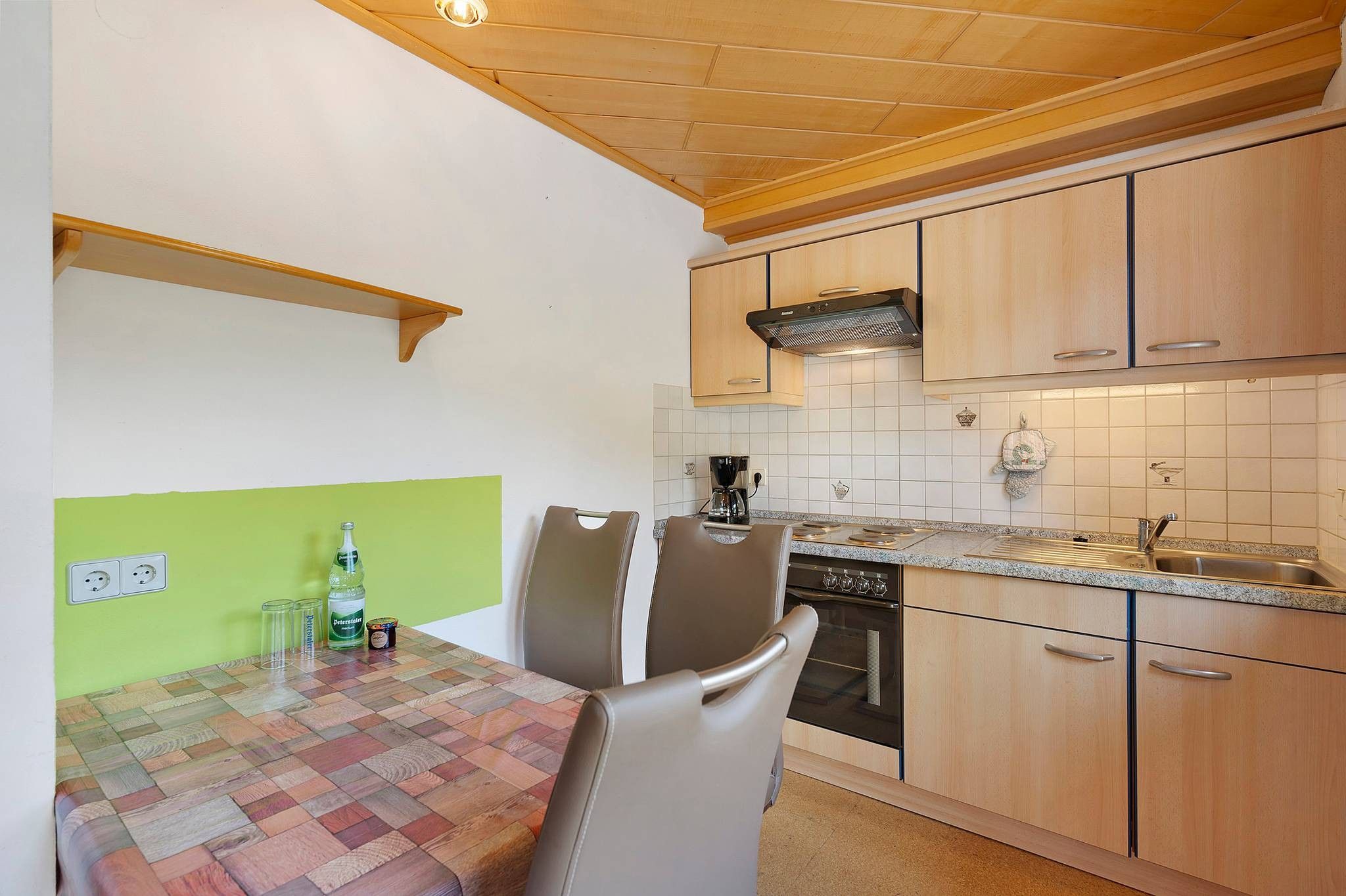 A compact kitchen with a dining table, chairs, a coffee maker, and a dishwasher.