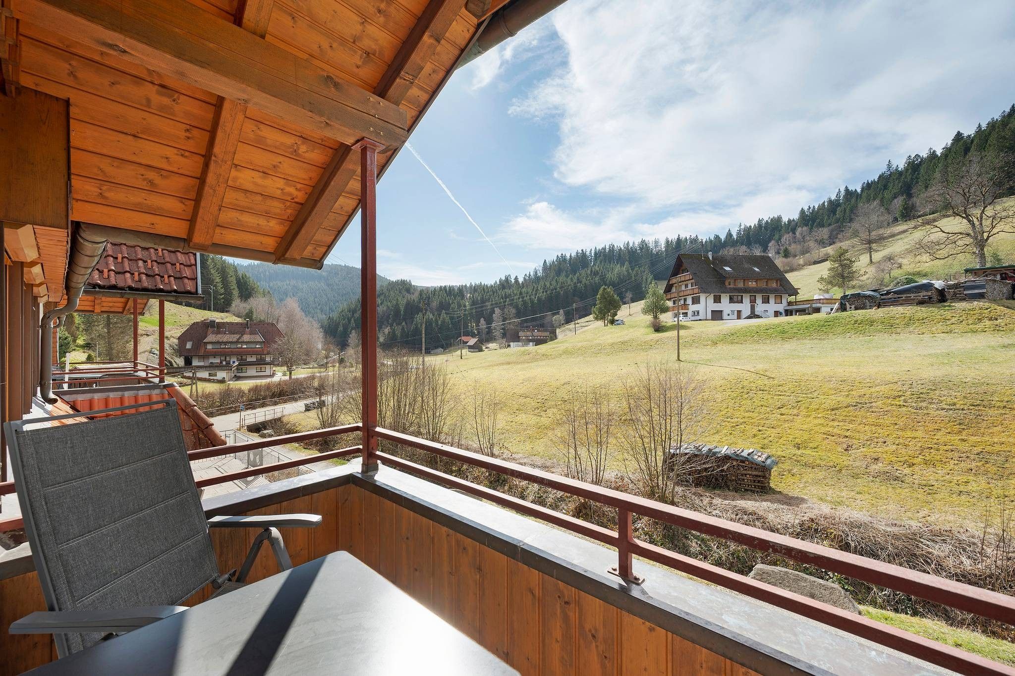 A wooden cabin with a balcony overlooking a rural landscape.