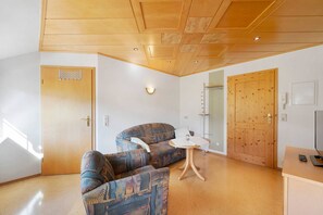 A room with a wooden ceiling, a sofa, a small table, and a door. - Holiday Apartment 'for 2 People' with Shared Garden, Balcony and Wi-Fi (Bad Rippoldsau-Schapbach)
