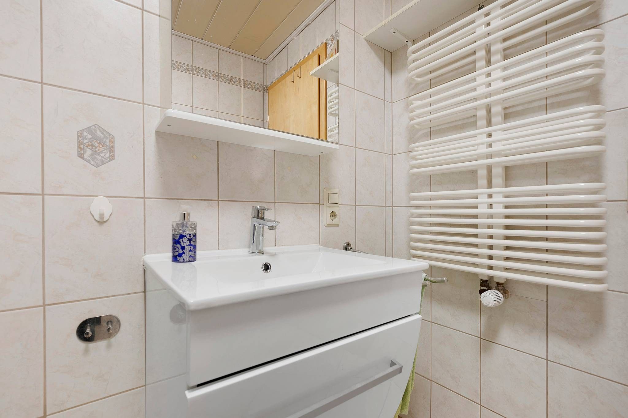 A bathroom with a white sink, a mirror, and a towel rack.