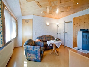 A room with a sofa, a small table, a television, and a radiator. - Holiday Apartment 'for 2 People' with Shared Garden, Balcony and Wi-Fi (Bad Rippoldsau-Schapbach)