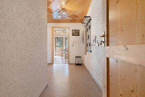 Un pasillo con una puerta de madera, una mesita con un objeto decorativo y un cuadro en la pared.